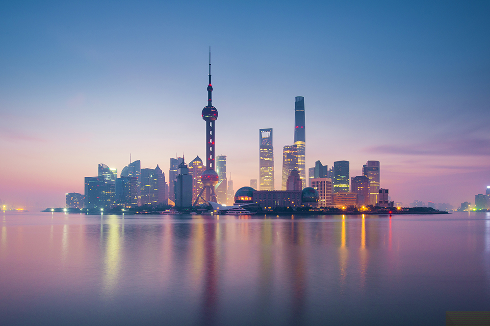 A layer of fog blankets the city as the sun sets behind the iconic Shanghai skyline (Photo by tonnaja.com / Getty Images)